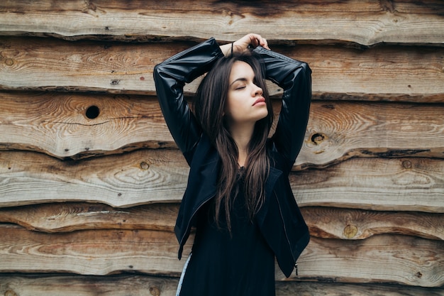 Mulher com olhos fechados perto da parede de madeira