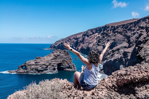 Mulher com os braços erguidos apreciando a bela vista da praia roque de santo domingo em la palma, nas ilhas canárias