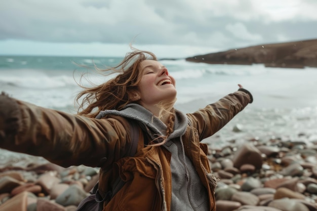 Foto mulher com os braços estendidos desfrutando do vento e respirando ar fresco na praia rochosa