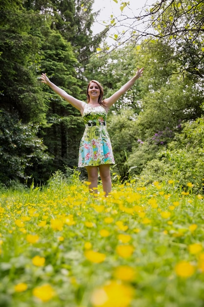 Foto mulher com os braços estendidos no campo contra as árvores