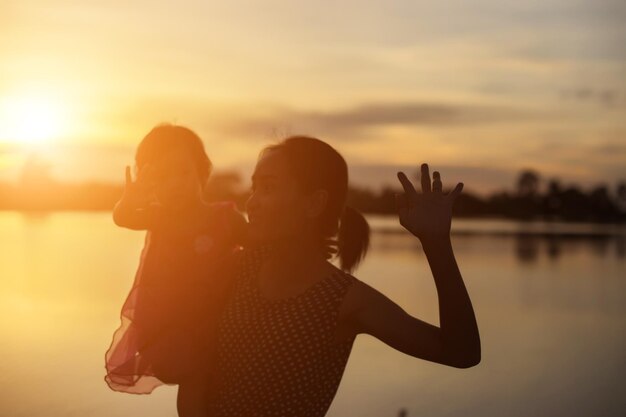 Mulher com os braços levantados de pé contra o céu durante o pôr do sol