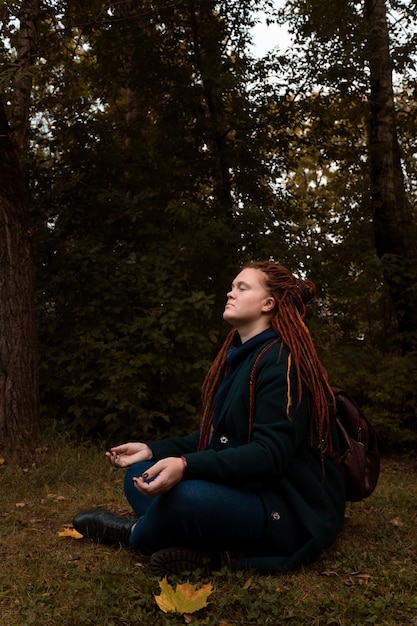 Foto mulher com os olhos fechados fazendo meditação na floresta sozinha
