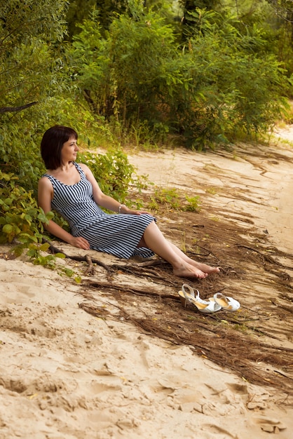 Mulher com os pés descalços na margem de um lago