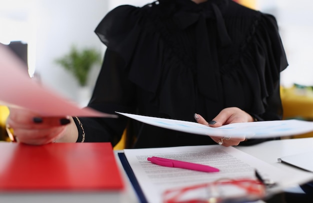 Mulher com papéis no braço sentada à mesa em close-up Trabalhador de colarinho branco no espaço de trabalho Oficial altamente remunerado inteligente caçador de cabeças sério oferece conceito de papelada