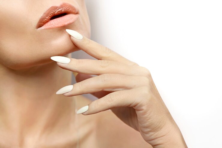 Foto mulher com pele limpa e saudável e uma longa manicure com esmalte de leite close-up.