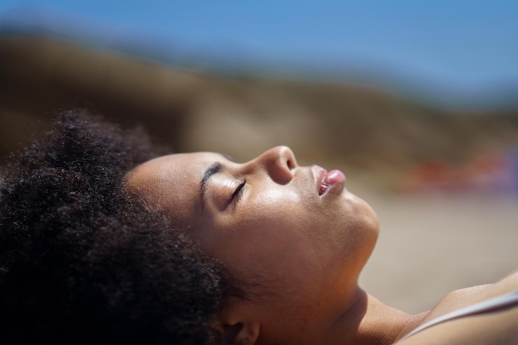 Foto mulher com penteado afro deitada na praia