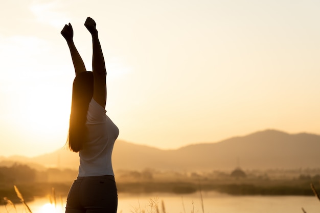 Foto mulher com punho no ar durante o conceito de pôr do sol, liberdade, força e coragem.