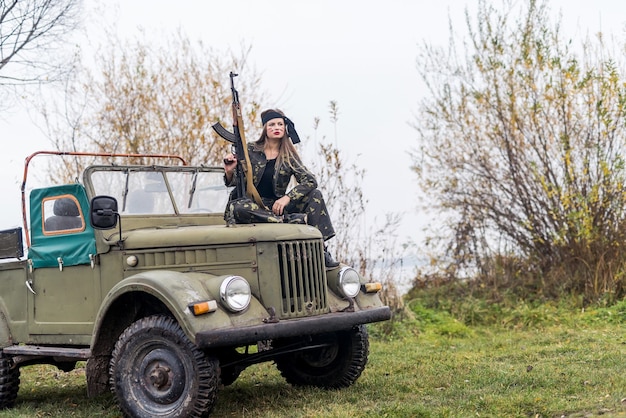 Mulher com rifle posando em carro militar