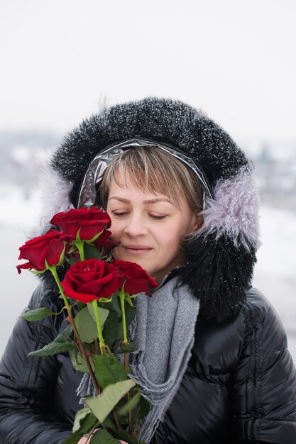 Mulher com rosas vermelhas ao ar livre no inverno