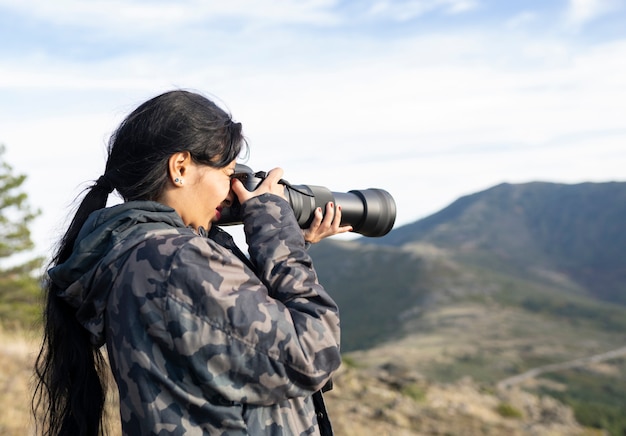 Mulher com roupas camufladas tirando fotos com lentes telefoto