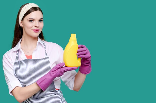 Mulher com roupas casuais e luvas de borracha segurando produtos de limpeza