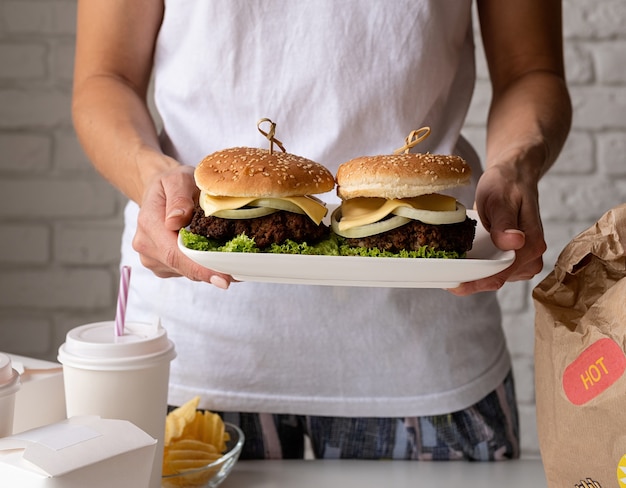 Foto mulher com roupas de casa desempacotando comida, entrega em domicílio com hambúrgueres, caixas de macarrão e bebidas