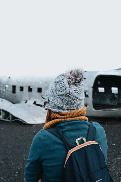 Mulher com roupas de inverno na frente do naufrágio do avião caiu na Islândia na praia de Solheimasandur Viagem para a Islândia conceito de viagem por estrada Copie a imagem do espaço visite a Islândia