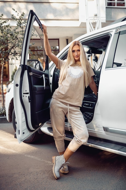 Mulher com roupas elegantes posando com um carro