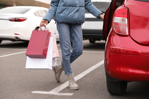 Foto mulher com sacolas de compras perto de seu carro ao ar livre closeup