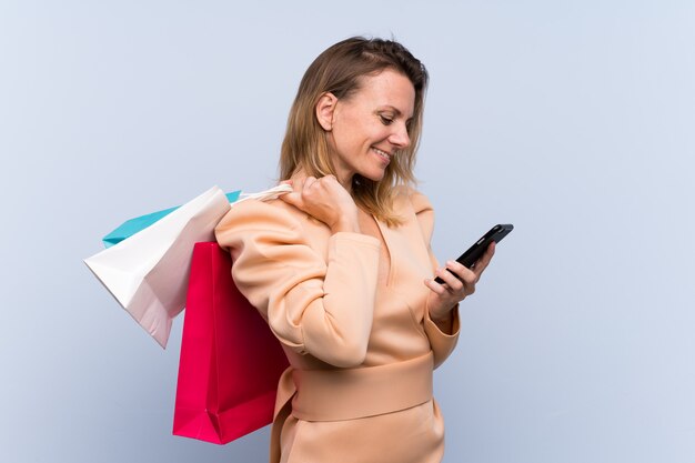 Foto mulher com sacos de compras sobre parede azul isolada