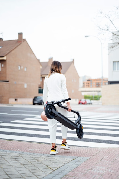 Mulher com scooter elétrica atravessando a rua