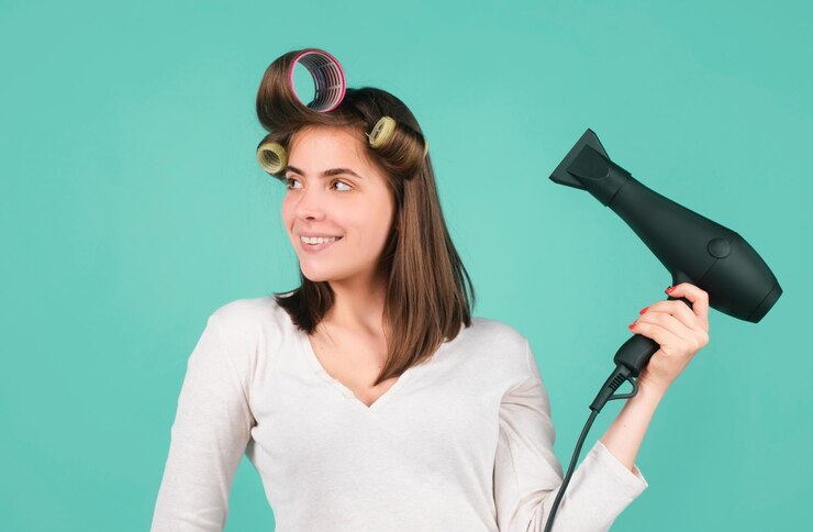 Foto mulher com secador de cabelo menina bonita com cabelo reto secando o cabelo com secadores de cabelo profissionais isolada em fundo azul