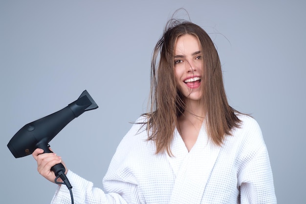 Mulher com secador de cabelo no fundo do estúdio garota segura secador de cabelo jovem secando cabelos com dr de cabelo