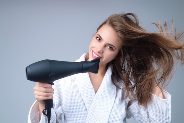 Foto mulher com secador de cabelo no fundo do estúdio garota segura secador de cabelo jovem secando cabelos com dr de cabelo