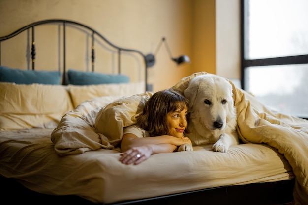 Mulher com seu cachorro debaixo do cobertor na cama