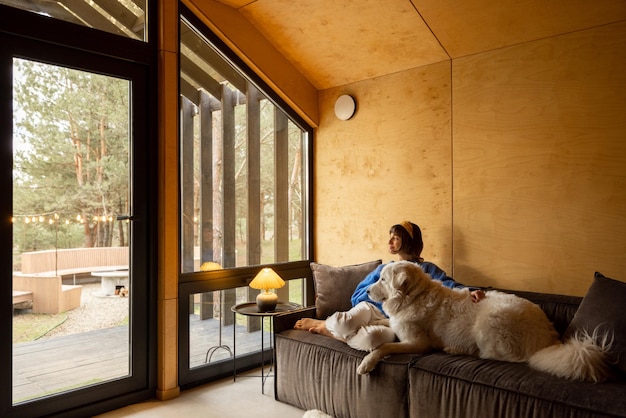 Mulher com seu cachorro em casa de madeira na natureza