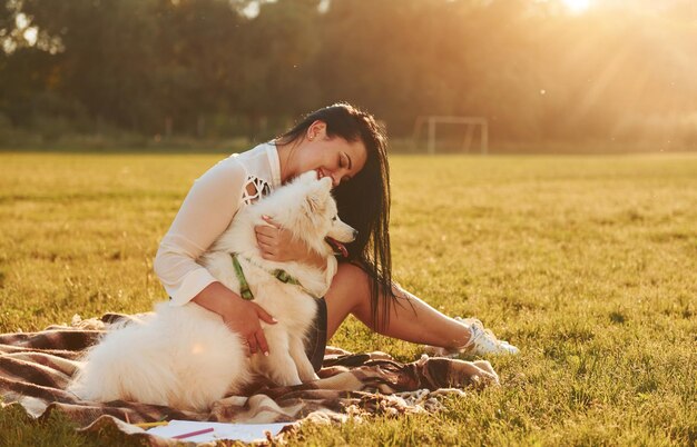 Mulher com seu cachorro está se divertindo no campo em dia ensolarado Belo sol