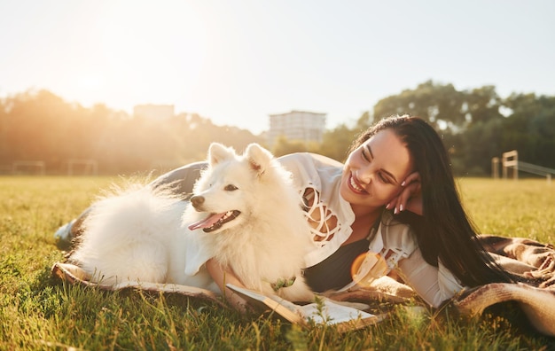 Mulher com seu cachorro está se divertindo no campo em dia ensolarado