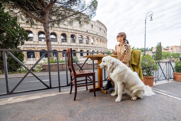 Mulher com seu cachorro no café ao ar livre em frente ao coliseu em roma itália