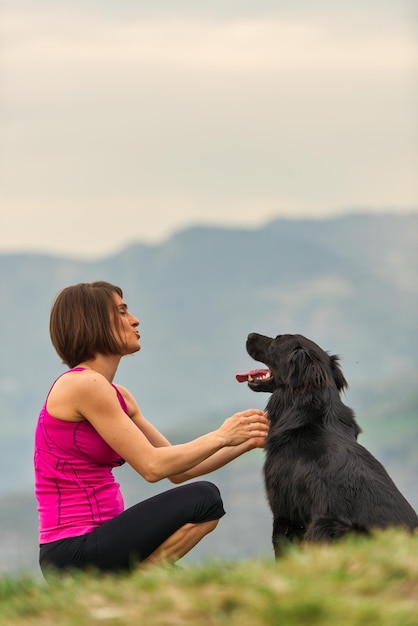 Mulher com seu cachorro preto nas montanhas