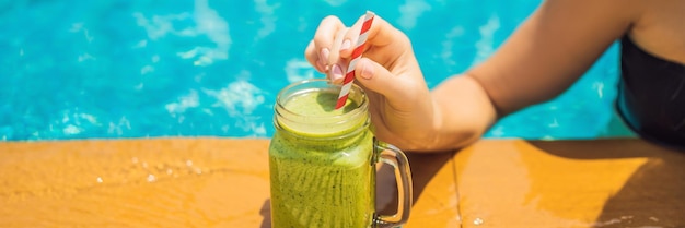 Mulher com smoothies verdes de espinafre e banana no fundo da piscina comida saudável