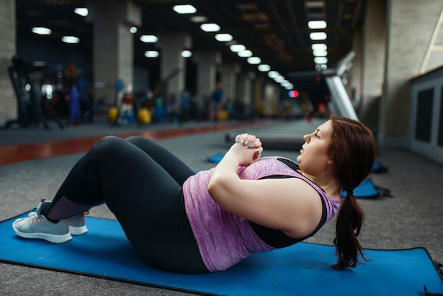 Foto mulher com sobrepeso fazendo exercícios no colchonete na academia, treinamento ativo