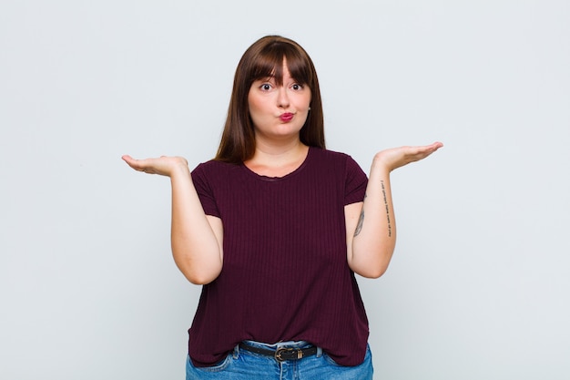 Foto mulher com sobrepeso se sentindo perplexa e confusa, duvidando, ponderando ou escolhendo diferentes opções com expressão engraçada