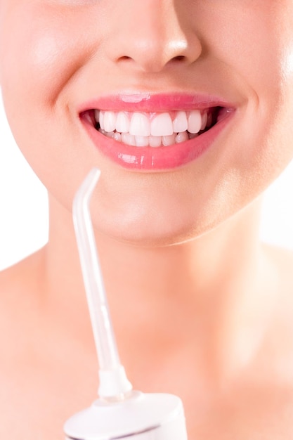 Mulher com sorriso branco perfeito usando fio dental portátil ou irrigador oral Cuidados bucais odontológicos