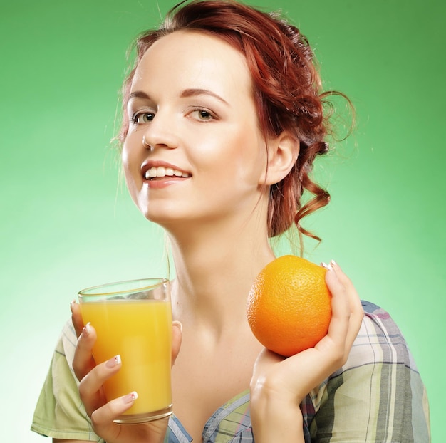 Mulher com suco de laranja sobre fundo verde