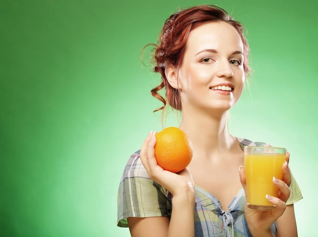 Mulher com suco de laranja sobre fundo verde