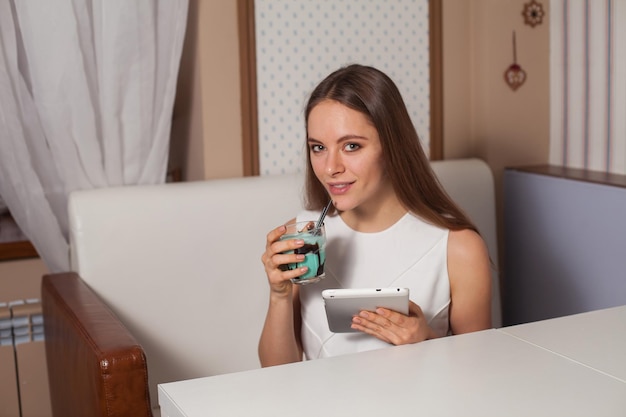 Mulher com tablet e bebida no café