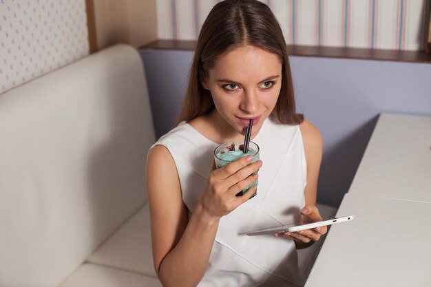 Mulher com tablet e bebida no café