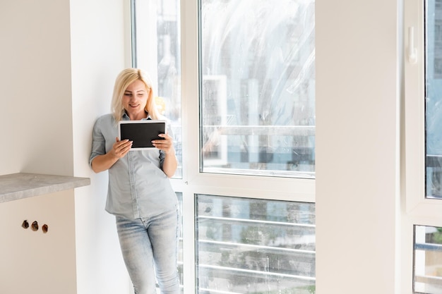 mulher com tablet procurando limpeza para lavar janela suja