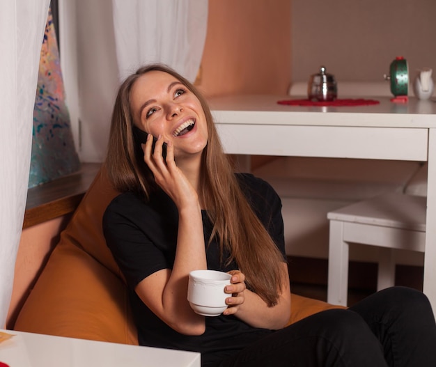 Mulher com telefone celular e xícara de café