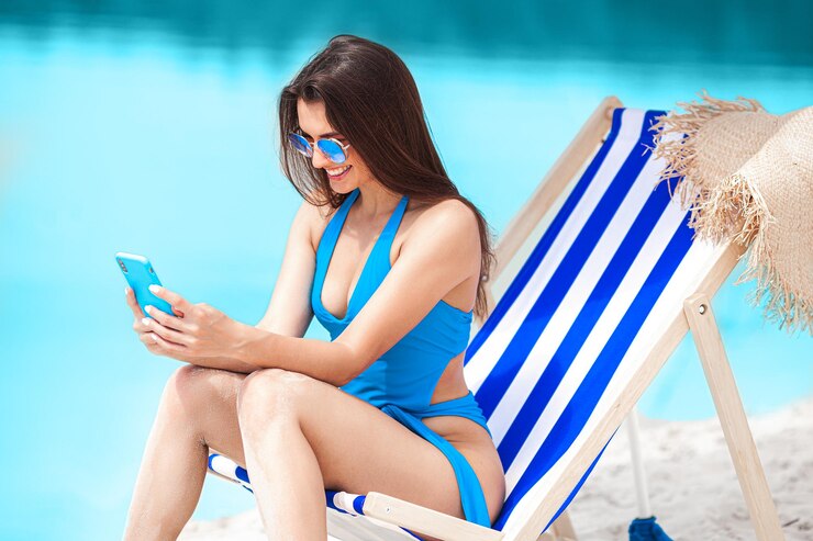 Mulher com telefone celular na praia no verão Senhora falando no telefone Mulher fazendo uma foto
