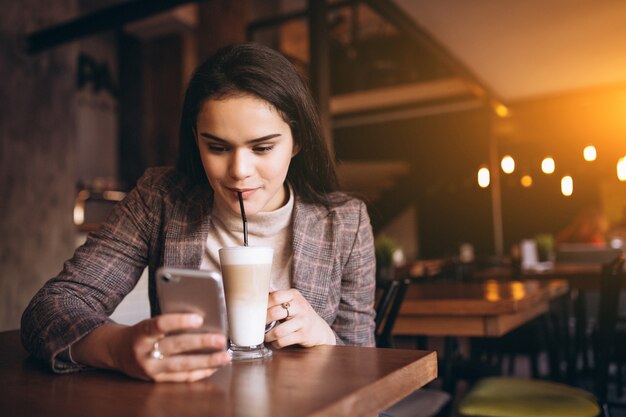 Mulher com telefone e café em um café