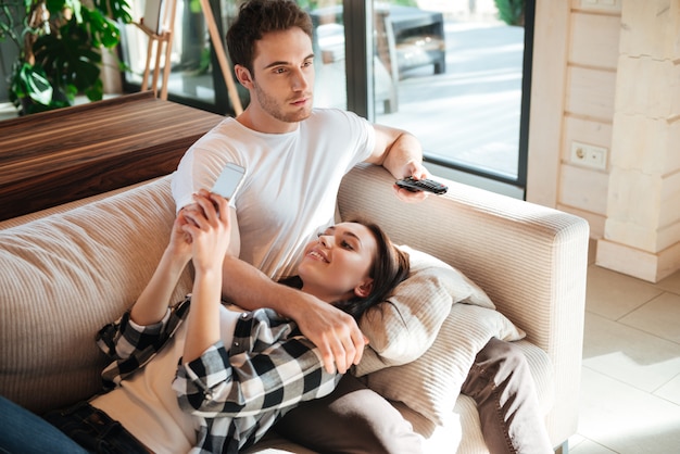 Mulher com telefone e homem com controle remoto