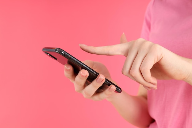 Foto mulher com telefone em um fundo rosa, close-up