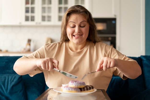 Mulher com transtorno alimentar tentando comer donuts