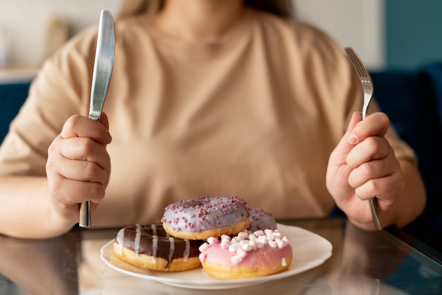 Foto mulher com transtorno alimentar tentando comer donuts