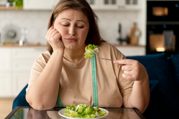 Foto mulher com transtorno alimentar tentando comer salada