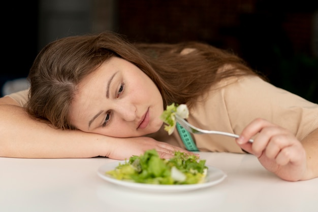 Mulher com transtorno alimentar tentando comer salada