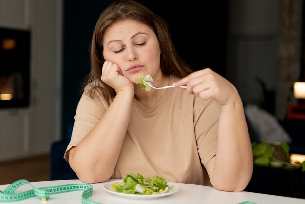 Foto mulher com transtorno alimentar tentando comer salada