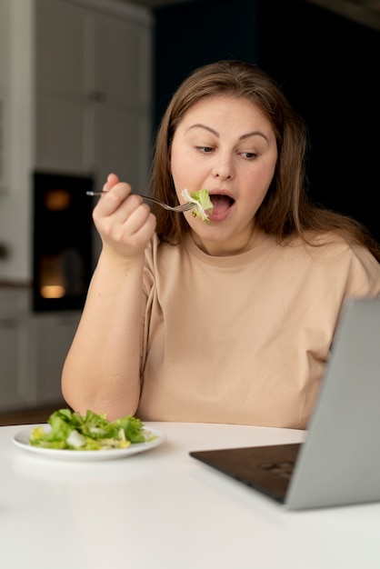 Foto mulher com transtorno alimentar tentando comer salada